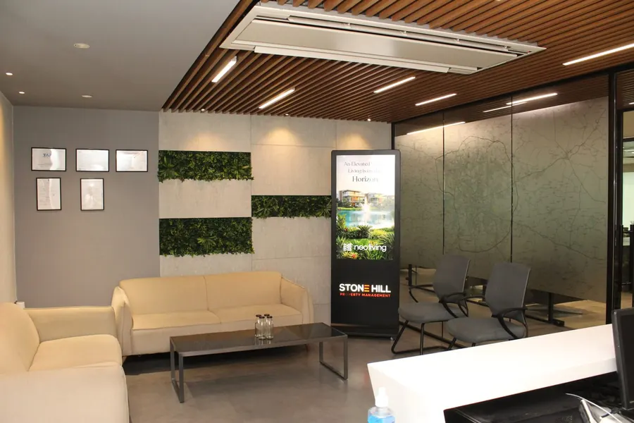 Waiting lounge with sofas and the Stone Hill standee at the Manikonda office