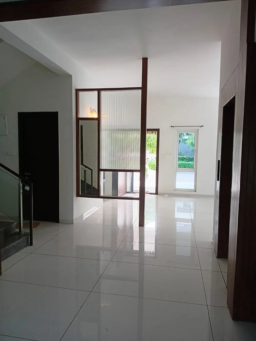 Tiled living hall of the Green Dale villa with wood-framed glass partition