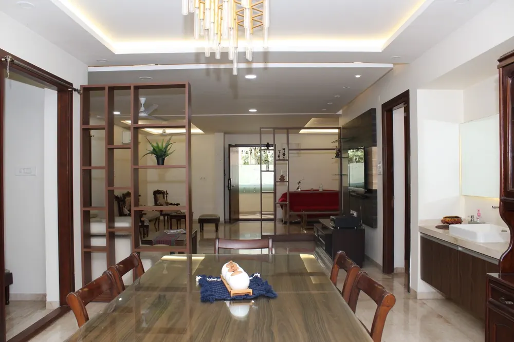 Dining and living area of the Royal One 3BHK, with wooden partition shelving and cove-lit ceiling