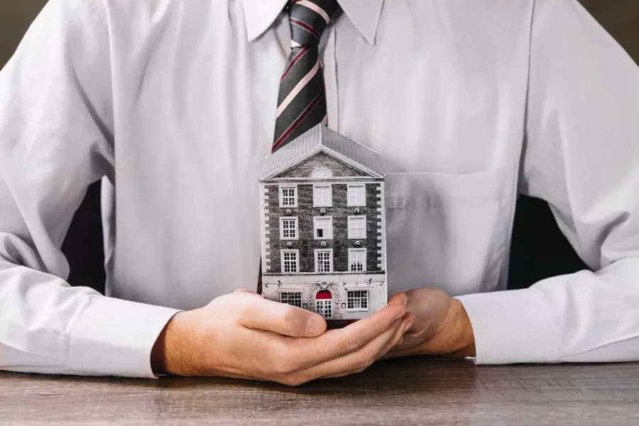 Hands holding a model house — owners protected by Stone Hill